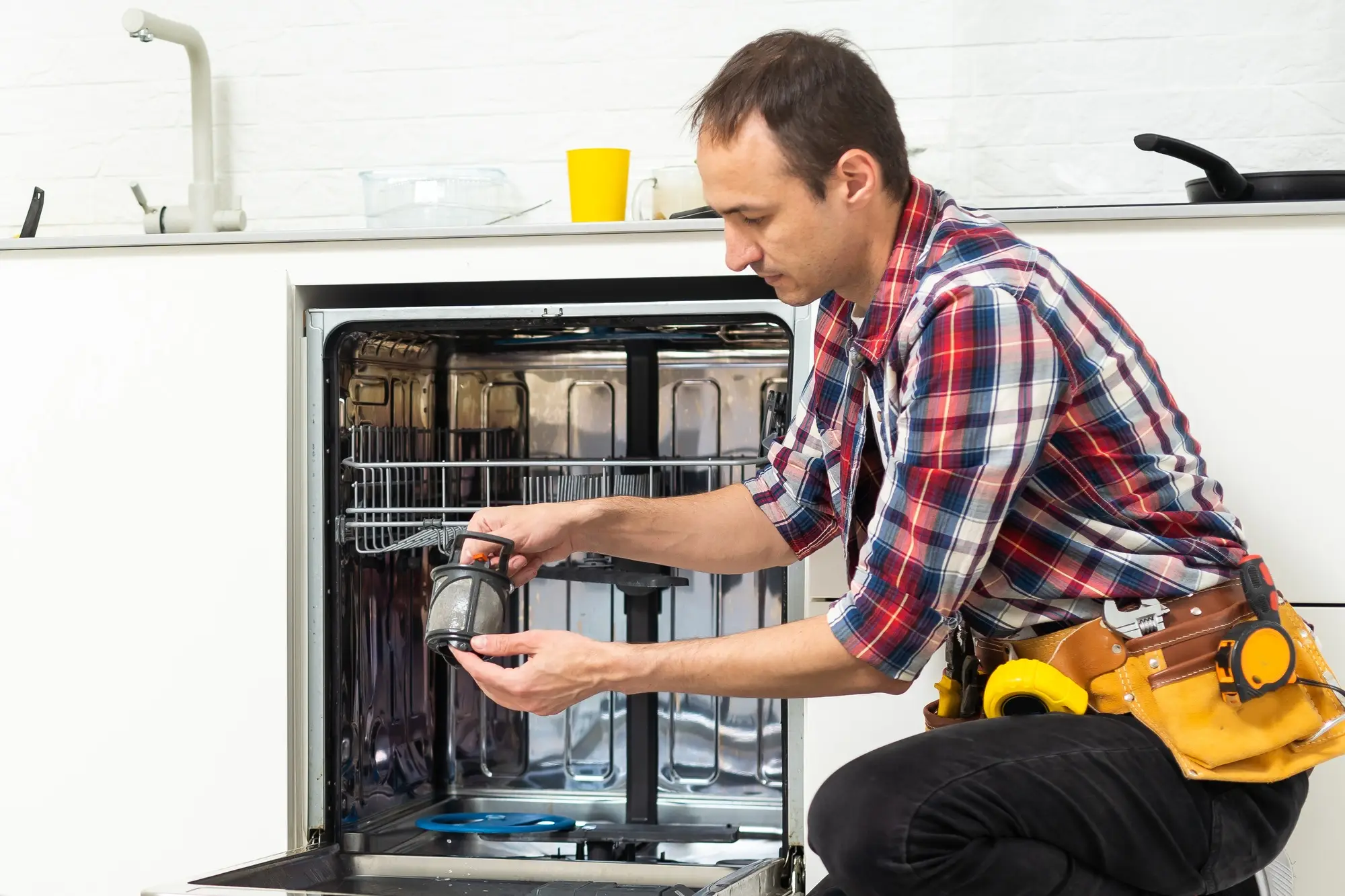 Plombier réparant une fuite de lave-vaisselle dans la cuisine